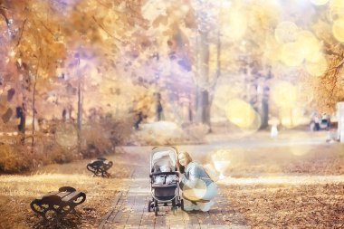 Annem sonbahar parkında yürüyüş için bebek arabasıyla gezer, sonbahar manzarası Ekim ayı sarı park manzarası
