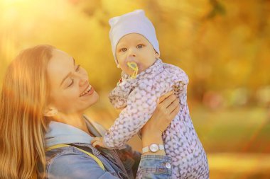 Anne bebeğini kucağında tutuyor, sonbahar parkında, açık havada aile geçmişi.