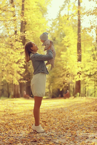 ママは秋の公園に赤ちゃんを投げる幸せ黄色の自然秋 — ストック写真