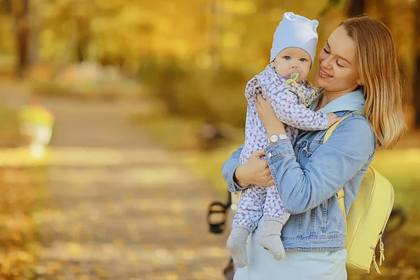 秋の公園で赤ちゃんを抱えてるママ屋外の家族の背景秋 — ストック写真