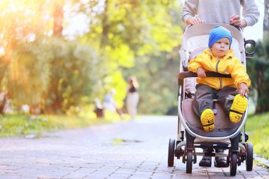 Sarı yağmurluklu çocuk, bak, sonbahar mevsimi parkta yürüyor.