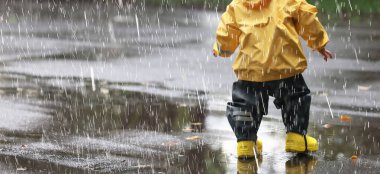 Yağmur yürüyüşü çocuk, sonbaharda parkta yağmur damlaları ve su birikintileri çocuk