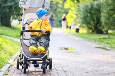 Sarı yağmurluklu çocuk, bak, sonbahar mevsimi parkta yürüyor.