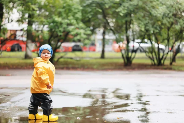 秋天在公园里小男孩穿着雨衣走着季节性的样子 — 图库照片