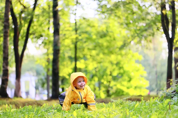 黄色雨衣男孩看 秋天季节漫步在公园里 — 图库照片