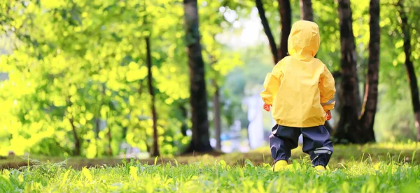 黄色いレインコートの少年公園を歩く秋の季節 — ストック写真