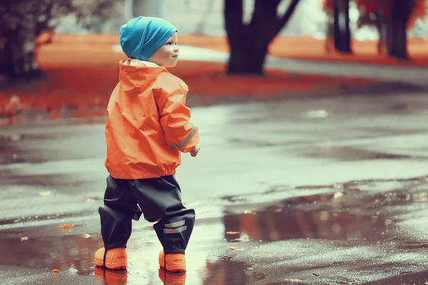 秋天在公园里小男孩穿着雨衣走着季节性的样子 — 图库照片
