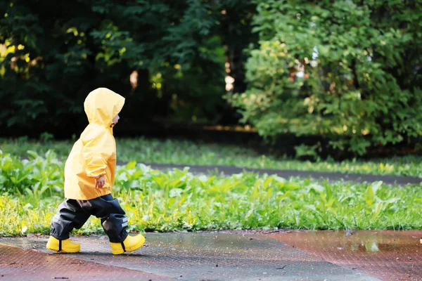 黄色いレインコートの少年公園を歩く秋の季節 — ストック写真