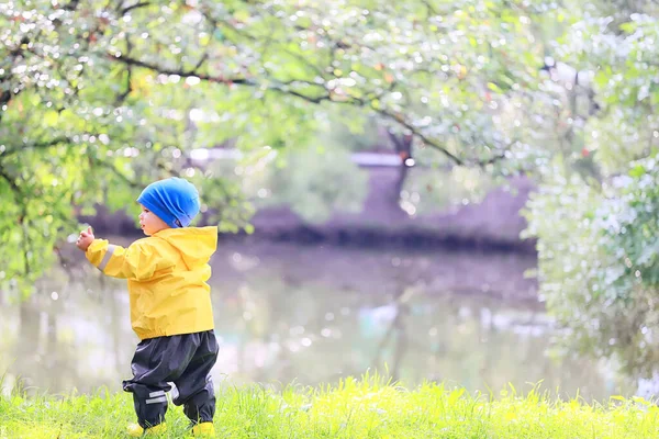 子供公園レインコート黄色 楽しい季節のぬれた防水屋外服 — ストック写真