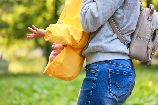 Sarı yağmurluklu çocuk, bak, sonbahar mevsimi parkta yürüyor.