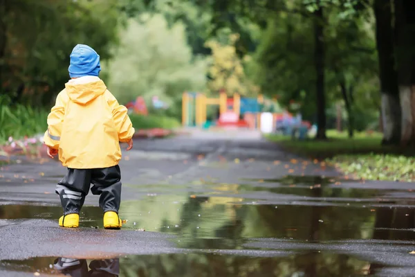 子供公園レインコート黄色 楽しい季節のぬれた防水屋外服 — ストック写真