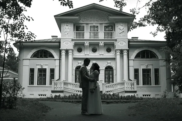 Bride and groom standing near beautiful mansion — Stock Photo, Image