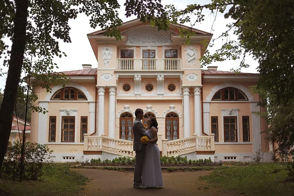 Bride and groom standing near beautiful mansion — Stock Photo, Image