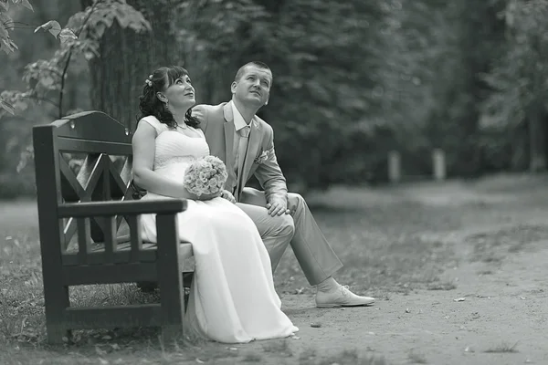 Bride and groom sitting on bench — Stock Photo, Image