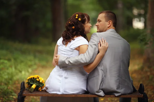 Bride and groom sitting on the bench — Stock Photo, Image