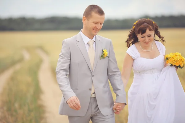 Bride and groom walking on wheat field — Stock Photo, Image