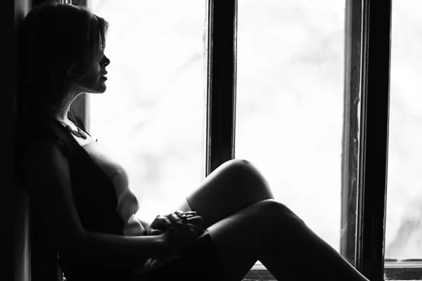 Woman sitting on the windowsill — Stock Photo, Image