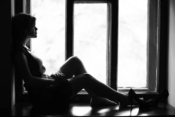 Frau sitzt auf der Fensterbank — Stockfoto