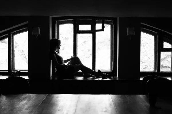 Brunette woman sitting on the windowsill — Stock Photo, Image