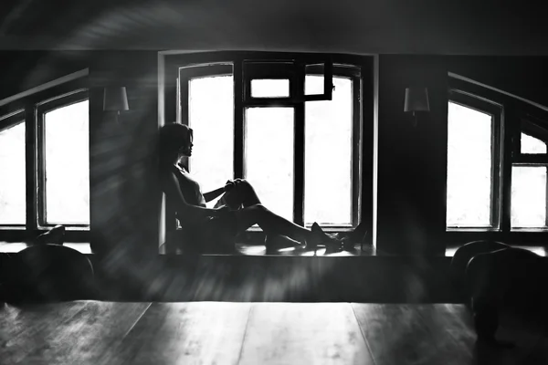 Brunette woman sitting on the windowsill — Stock Photo, Image