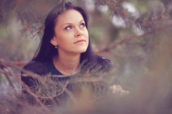 Girl looking through fir tree branches — Stock Photo, Image