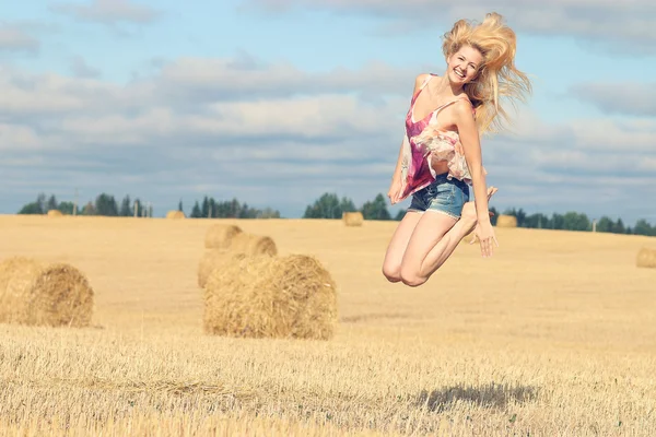 Blonde vrouw springt in veld — Stockfoto
