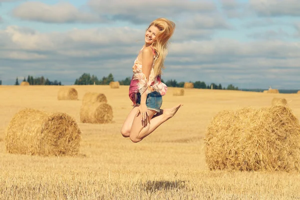 Blonde woman jumps in field — Stock Photo, Image