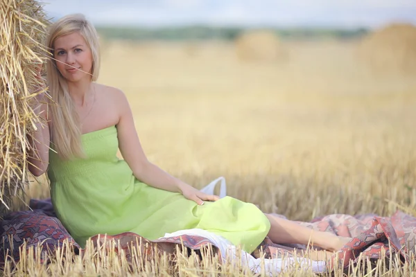Blonde Frau sitzt neben dem Heu — Stockfoto