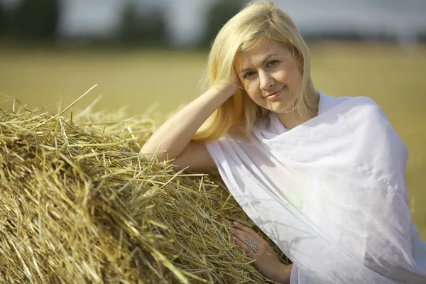 Blond kvinna sitter nära hö — Stockfoto