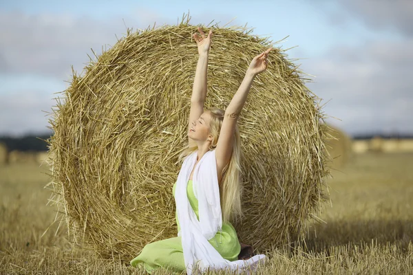 Blond woman sitting near the hay — Stock Photo, Image