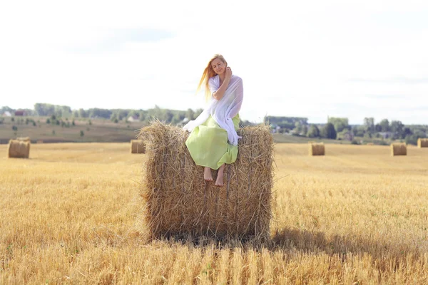 Blond kobieta siedzi na siano — Zdjęcie stockowe