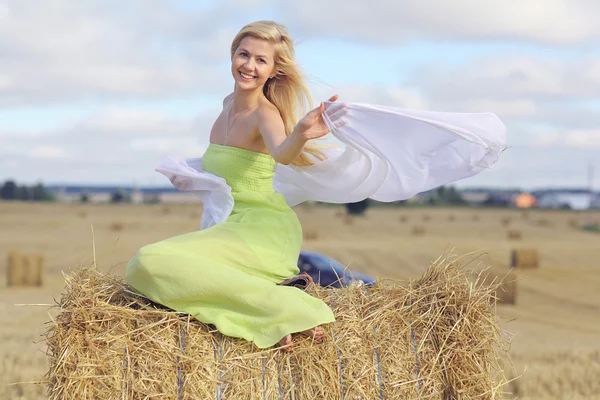 Blonde vrouw zittend op het hooi — Stockfoto