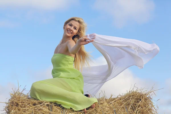 Blonde Frau sitzt auf dem Heu — Stockfoto