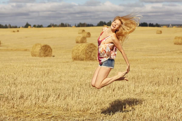 Blondýnka skáče v poli — Stock fotografie