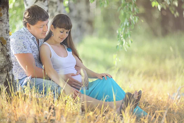 Man och en gravid kvinna liggande på gräset — Stockfoto