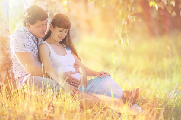男人和一个怀孕的女人躺在草地上 — 图库照片