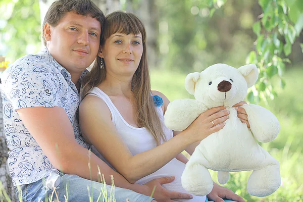 Мужчина и беременная женщина держат игрушечного медведя — стоковое фото