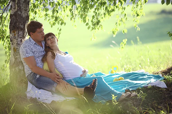 Man en een zwangere vrouw liggen op het gras — Stockfoto