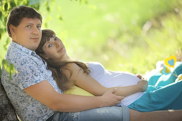 Hombre y una mujer embarazada tumbados en la hierba — Foto de Stock