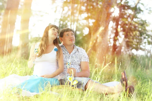 Homme et une femme enceinte assis sur l'herbe — Photo