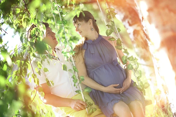 Man and a pregnant woman on the swing — Stock Photo, Image