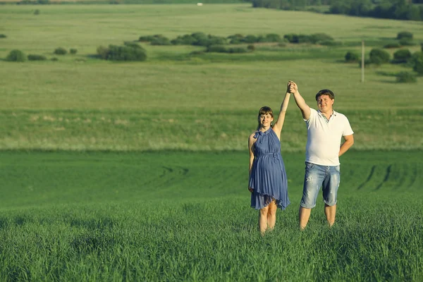 Man and a pregnant woman in field — Stock Photo, Image