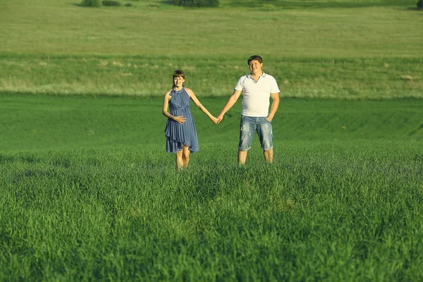 Man and a pregnant woman in field — Stock Photo, Image