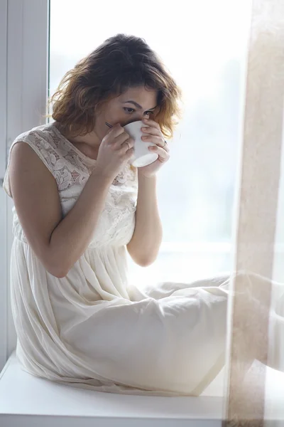 Chica bebiendo té en alféizar de la ventana — Foto de Stock