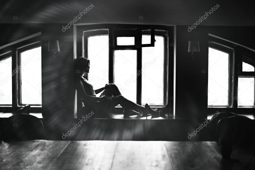Brunette woman sitting on the windowsill