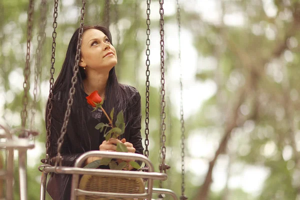 Ragazza con fiore su altalena — Foto Stock