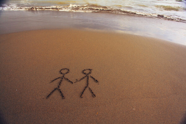 Пара человек рисует на песке

