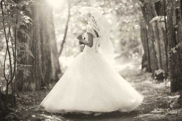 Portrait of bride with umbrella in forest