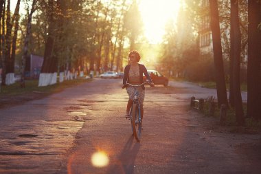 Girl on bike at sunset clipart