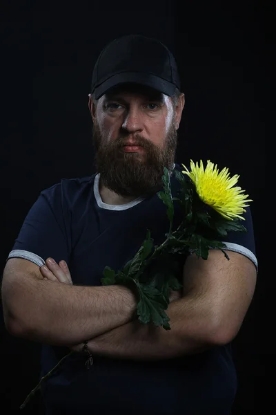 Barbudo hombre brutal con una flor — Foto de Stock